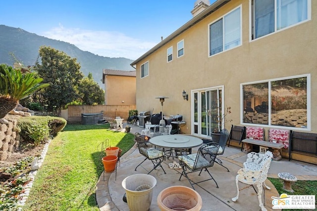 back of property featuring a yard, a mountain view, and a patio