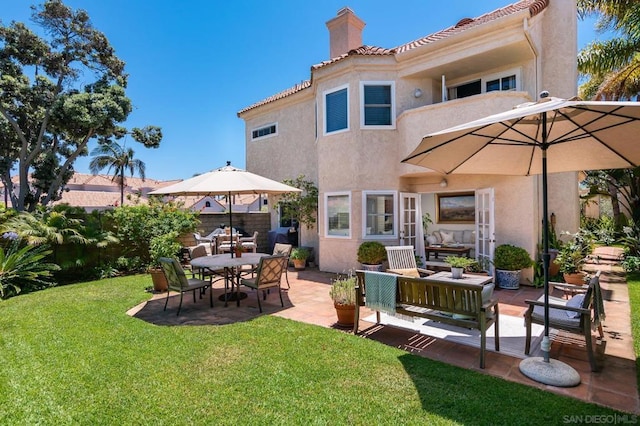 rear view of property with a lawn, an outdoor living space, and a patio