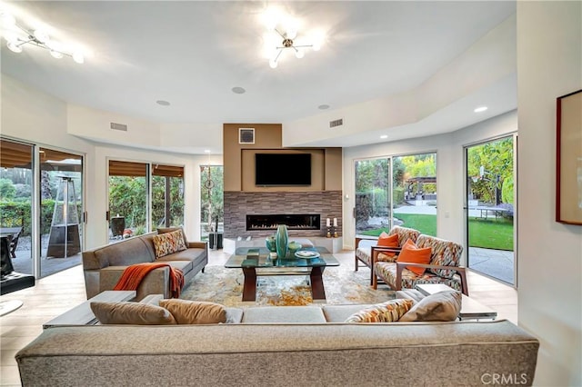 living area with a warm lit fireplace, visible vents, and recessed lighting