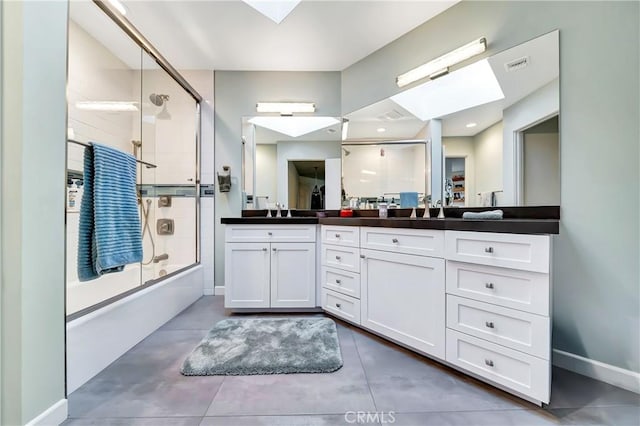 bathroom featuring a skylight, visible vents, enclosed tub / shower combo, vanity, and baseboards