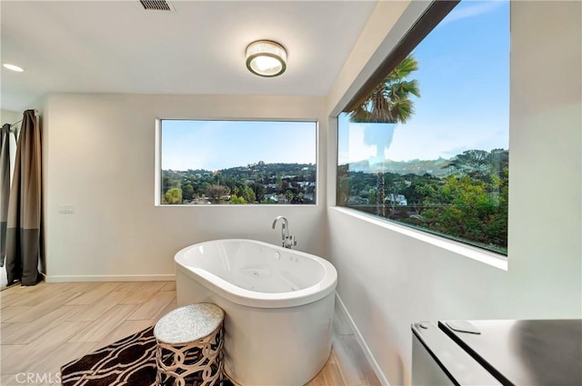 full bathroom featuring a freestanding bath and baseboards