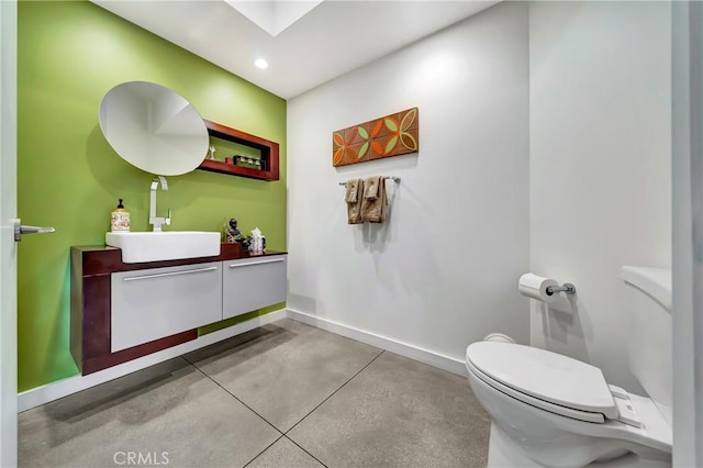 half bath with a skylight, finished concrete flooring, toilet, and vanity