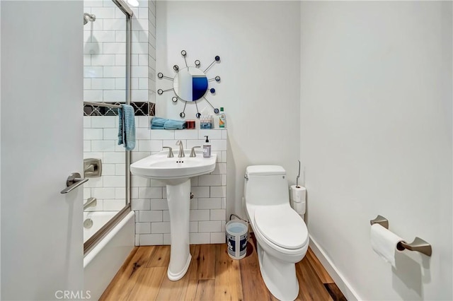 full bath with washtub / shower combination, baseboards, toilet, and wood finished floors