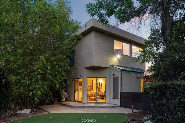 rear view of property with metal roof, fence, stucco siding, a standing seam roof, and a patio area