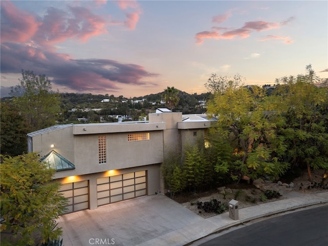 view of front of home with a garage, concrete driveway, and stucco siding