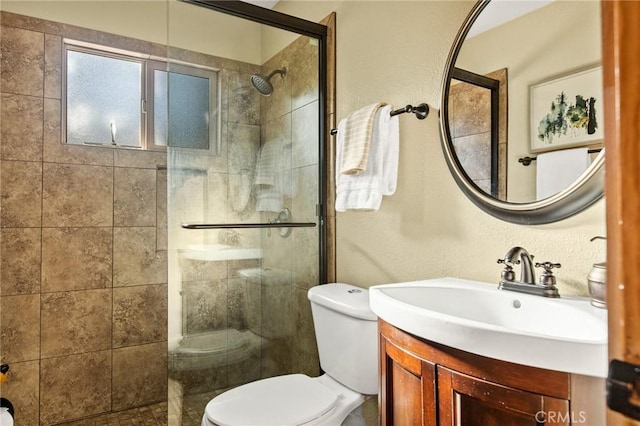 bathroom featuring toilet, a shower with shower door, and vanity