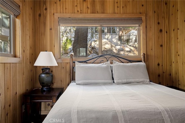 bedroom with wood walls and multiple windows