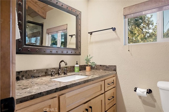 bathroom with toilet, vaulted ceiling with beams, and vanity