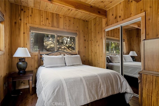 bedroom featuring wood walls, a closet, beam ceiling, and wood ceiling