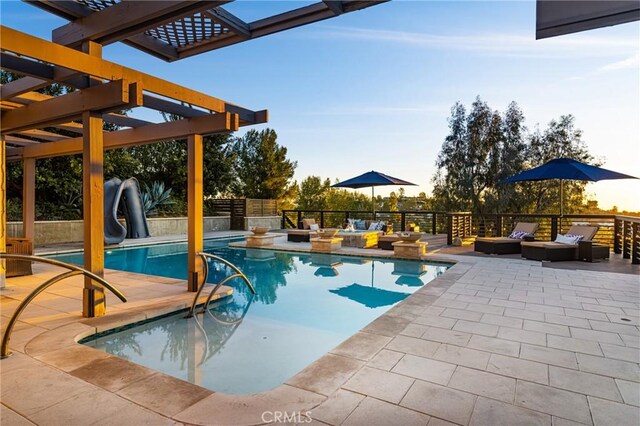 pool at dusk featuring a water slide, a pergola, and a patio area