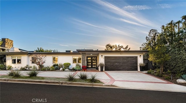 view of front of property with a garage, concrete driveway, french doors, and stucco siding