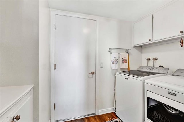 clothes washing area featuring dark wood-type flooring, cabinets, and washing machine and clothes dryer