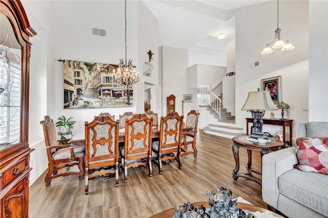 dining area featuring light hardwood / wood-style floors, a high ceiling, and a notable chandelier