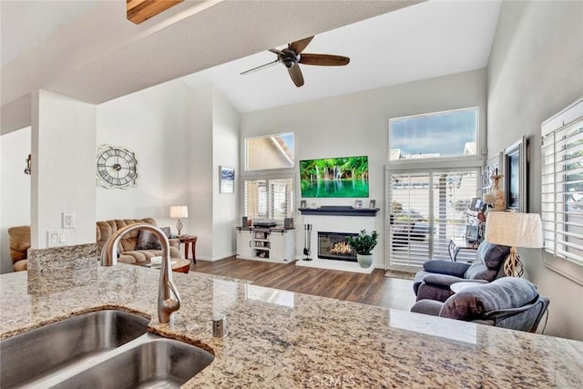 kitchen featuring ceiling fan, sink, light stone counters, and hardwood / wood-style floors