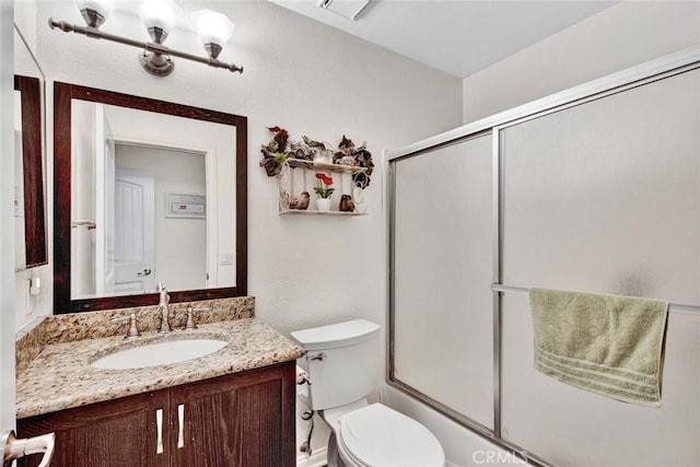 full bathroom featuring combined bath / shower with glass door, vanity, and toilet