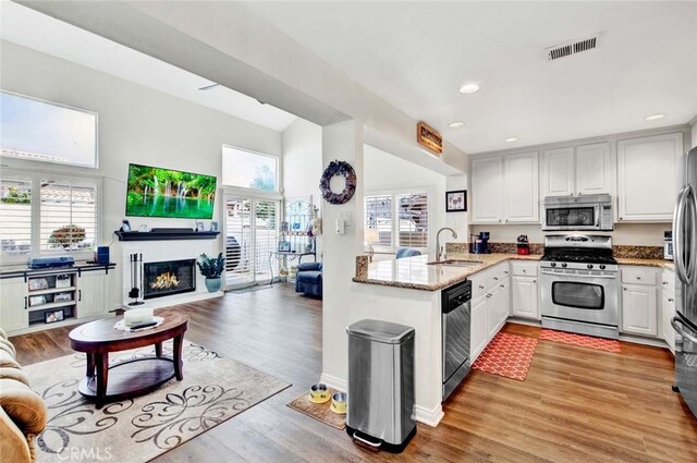 kitchen with white cabinets, appliances with stainless steel finishes, light hardwood / wood-style floors, sink, and kitchen peninsula