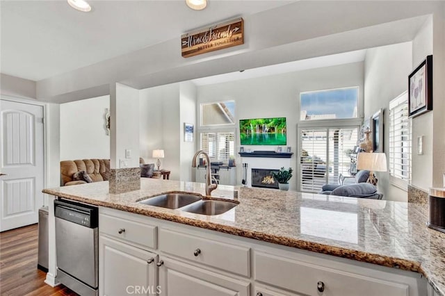 kitchen with light stone counters, sink, white cabinets, and dishwasher