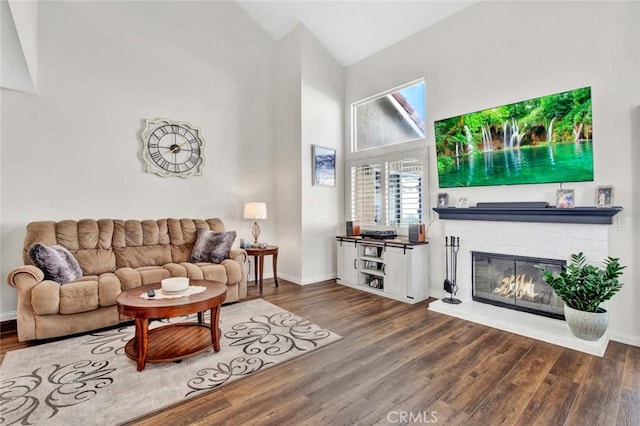 living room with high vaulted ceiling, a fireplace, and hardwood / wood-style floors