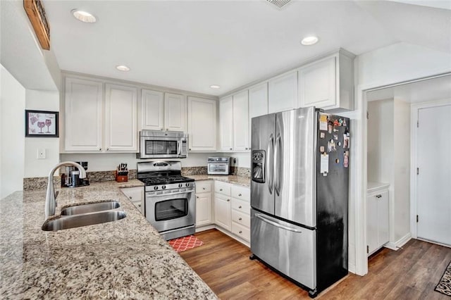 kitchen featuring white cabinets, appliances with stainless steel finishes, sink, and light stone counters