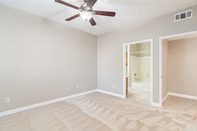 unfurnished bedroom with ceiling fan, light colored carpet, and ensuite bath