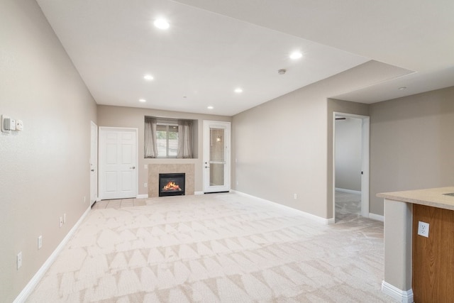 unfurnished living room featuring light colored carpet and a tiled fireplace