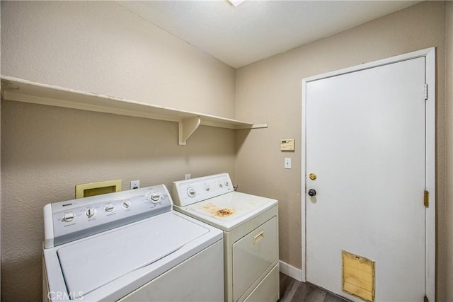 clothes washing area with dark wood-type flooring and separate washer and dryer