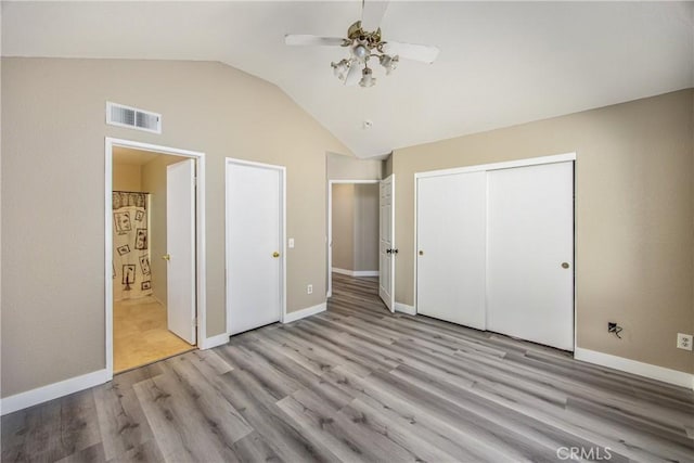 unfurnished bedroom with vaulted ceiling, ensuite bathroom, ceiling fan, light wood-type flooring, and a closet