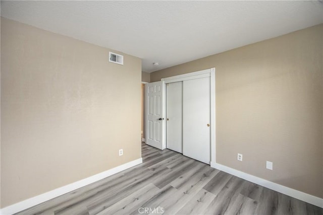 unfurnished bedroom with light hardwood / wood-style floors and a closet