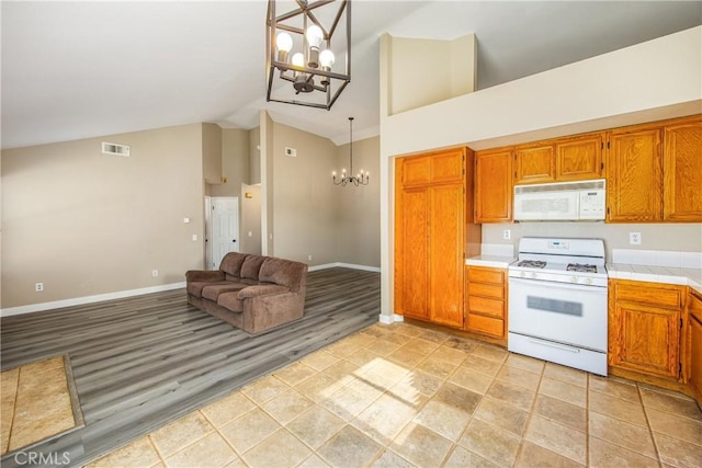 kitchen featuring high vaulted ceiling, decorative light fixtures, a chandelier, white appliances, and light hardwood / wood-style flooring