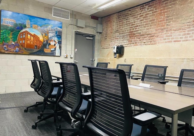 home office with a drop ceiling and brick wall