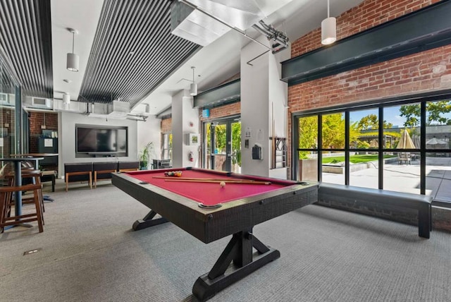 recreation room featuring carpet floors, billiards, a towering ceiling, and brick wall