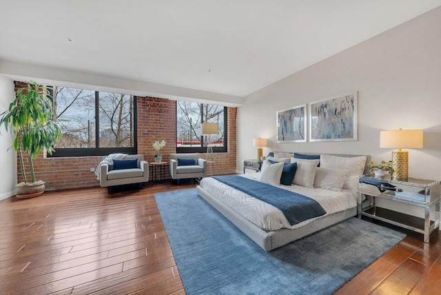 bedroom featuring brick wall and dark hardwood / wood-style floors