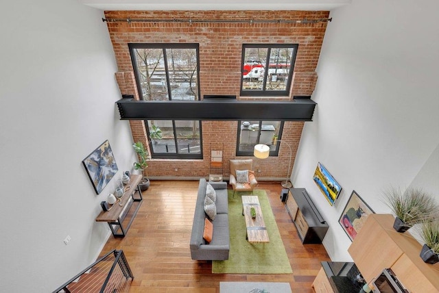 living room with light wood-type flooring, brick wall, and a high ceiling