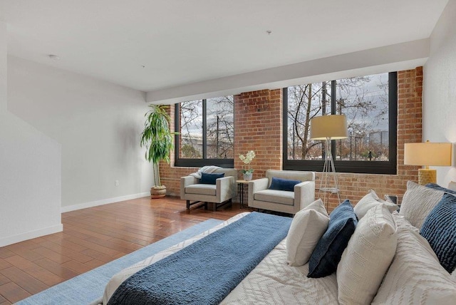 bedroom with hardwood / wood-style flooring and brick wall