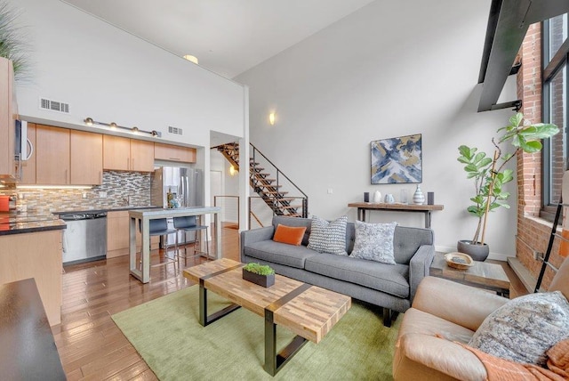 living room featuring a towering ceiling and light hardwood / wood-style flooring