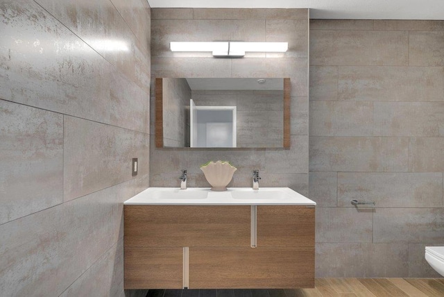 bathroom featuring toilet, vanity, and tile walls