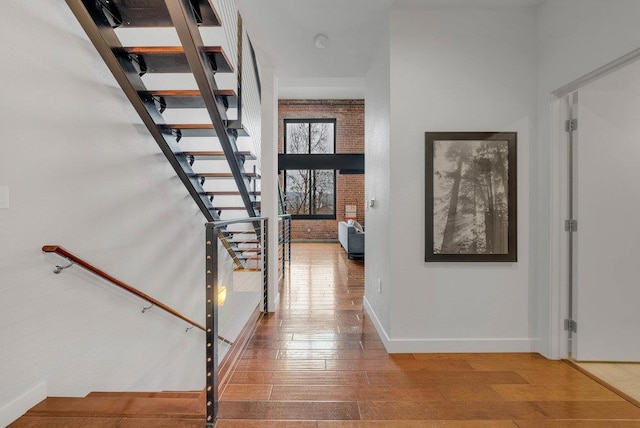 entryway with brick wall and hardwood / wood-style flooring