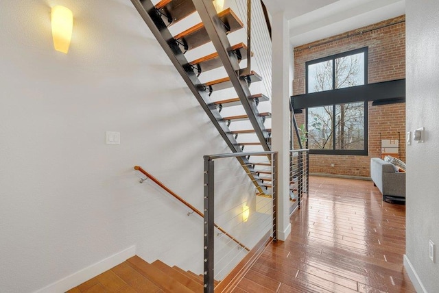 stairway featuring brick wall and wood-type flooring