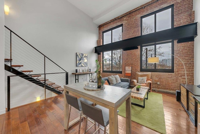 interior space featuring wood-type flooring, brick wall, and a high ceiling