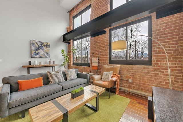 living room featuring brick wall, a high ceiling, and hardwood / wood-style flooring