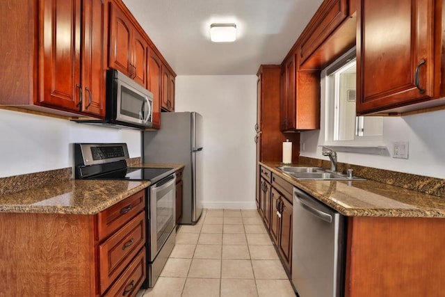 kitchen featuring dark stone countertops, sink, light tile patterned floors, and appliances with stainless steel finishes