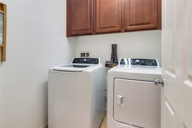 washroom with light tile patterned floors, independent washer and dryer, and cabinets