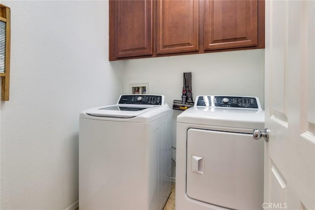 clothes washing area featuring separate washer and dryer and cabinet space