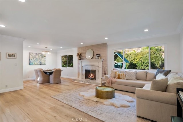 living room with a fireplace, ornamental molding, light hardwood / wood-style floors, and a notable chandelier