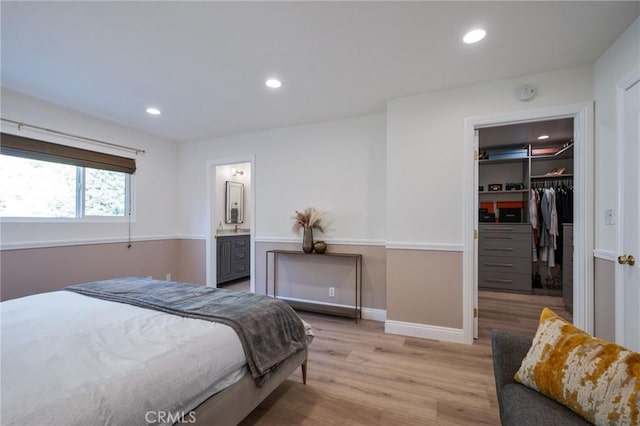 bedroom featuring a walk in closet, a closet, connected bathroom, and light hardwood / wood-style flooring