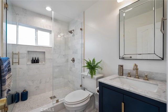 bathroom with a shower with shower door, toilet, and vanity