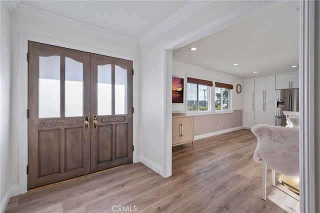 foyer entrance featuring french doors, ornamental molding, and light hardwood / wood-style flooring