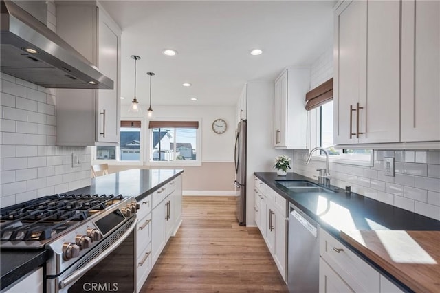 kitchen featuring stainless steel appliances, white cabinets, and wall chimney range hood