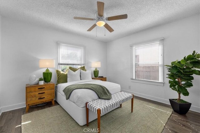 bedroom featuring ceiling fan, multiple windows, dark hardwood / wood-style flooring, and a textured ceiling