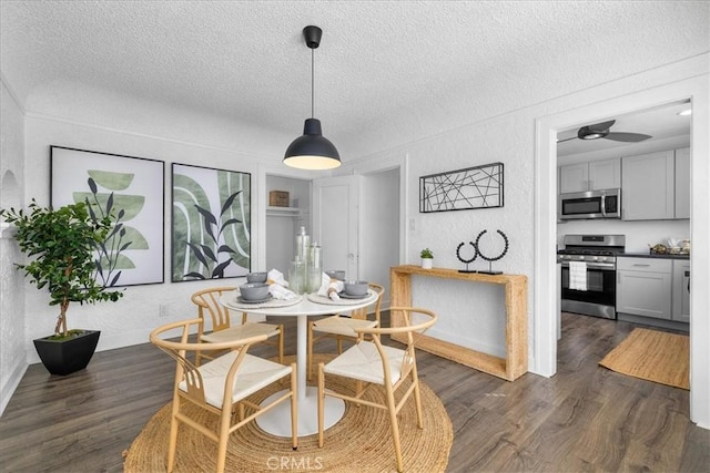 dining space featuring ceiling fan, dark wood-type flooring, and a textured ceiling